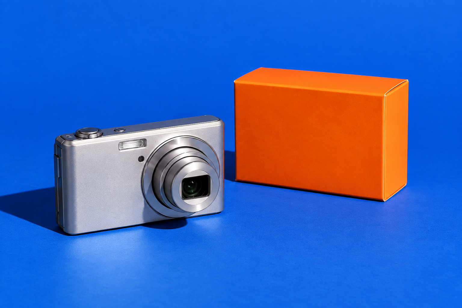 A camera and a bright orange product package in a blue creative studio